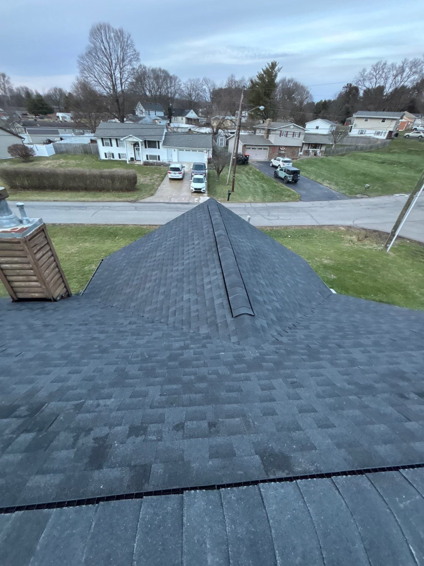 Roofer lifting a wind damaged shingle to show a broken seal strip